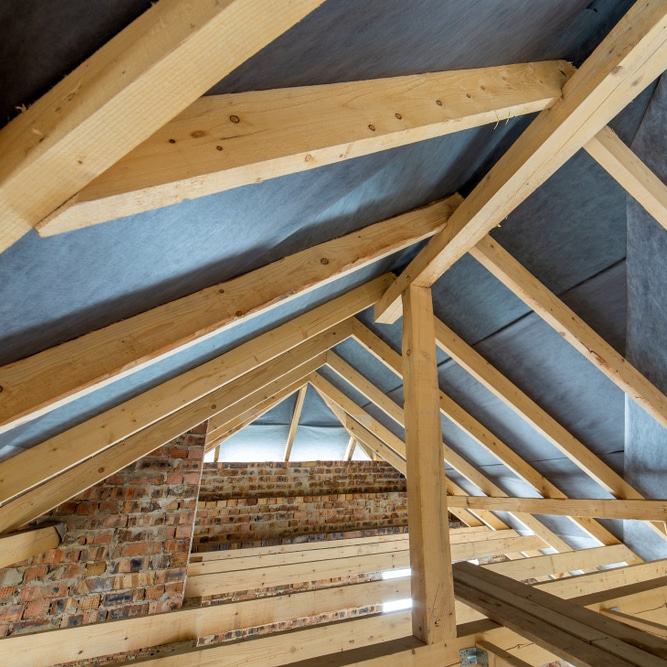 Construction de Charpente en Bois pour Toiture de Maison Charpente bois apparente sous toiture en construction avec membrane protectrice et poutres massives.