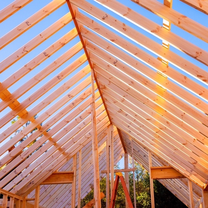 Construction de charpente en bois pour toit de maison Charpente en bois d'un toit en construction sous un ciel bleu dégagé avec une échelle orange au milieu.